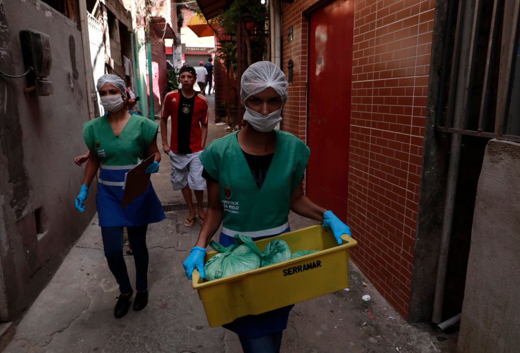Unos voluntarios entregan alimentos a los habitantes de la favela Paraisopolis en Sao Paulo