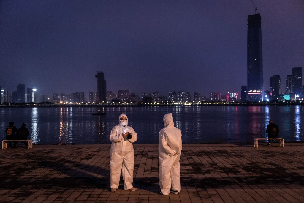 Un par de ciudadanos chinos se fotografían con trajes sanitarios en una plaza de la ciudad de Wuhan