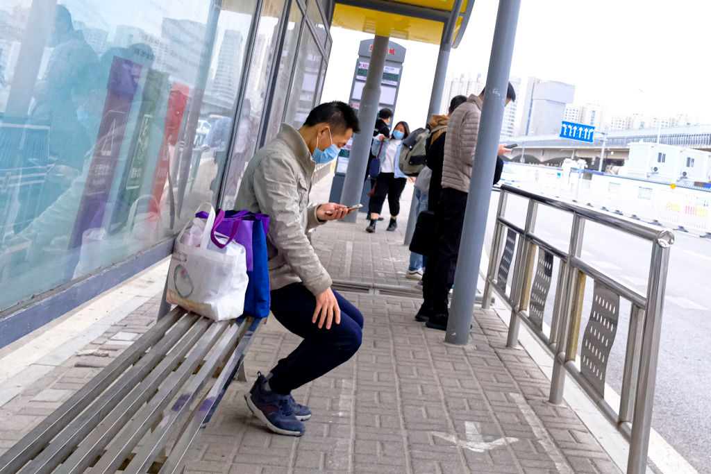 Un trabajador utiliza una máscara en un paradero de buses en la capital de China