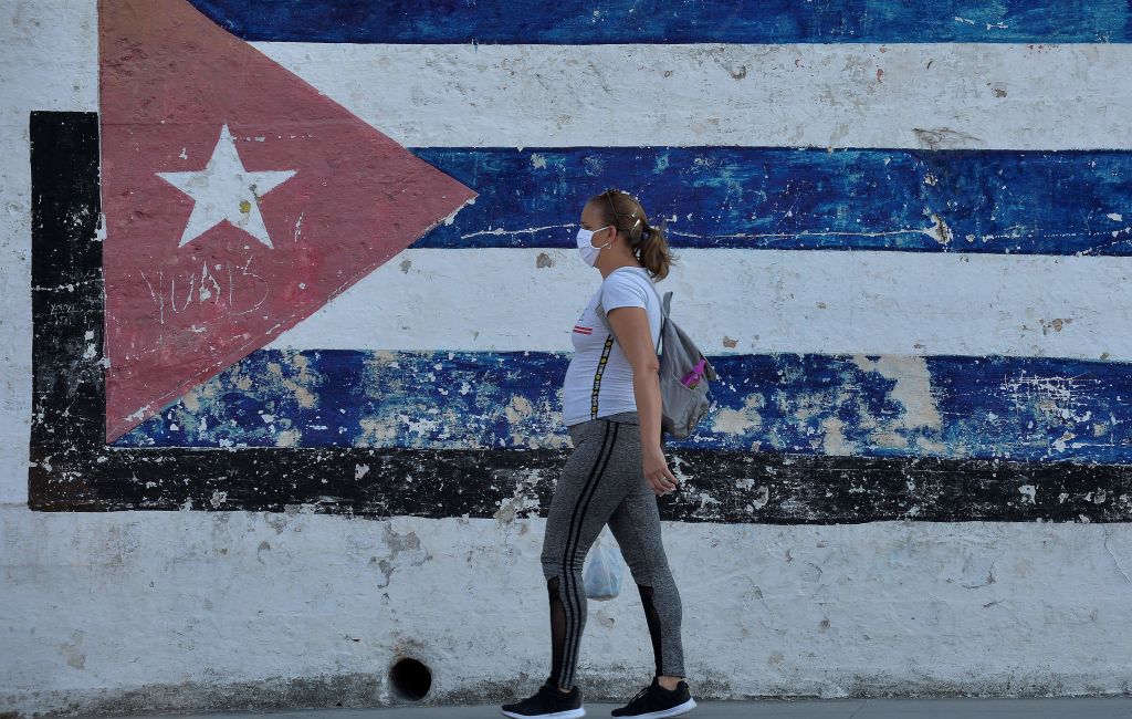 Una mujer utiliza una máscara mientras camina por la ciudad de La Habana