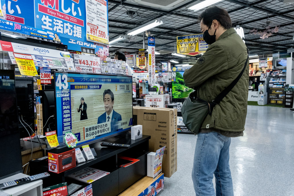 Una persona observa el mensaje del primer ministro japonés en una televisión