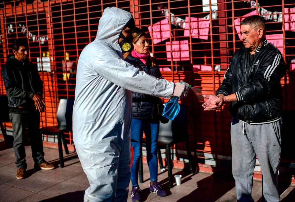 Un trabajador sanitario entrega alcohol a las personas en la municipalidad argentina de José Carlos Paz