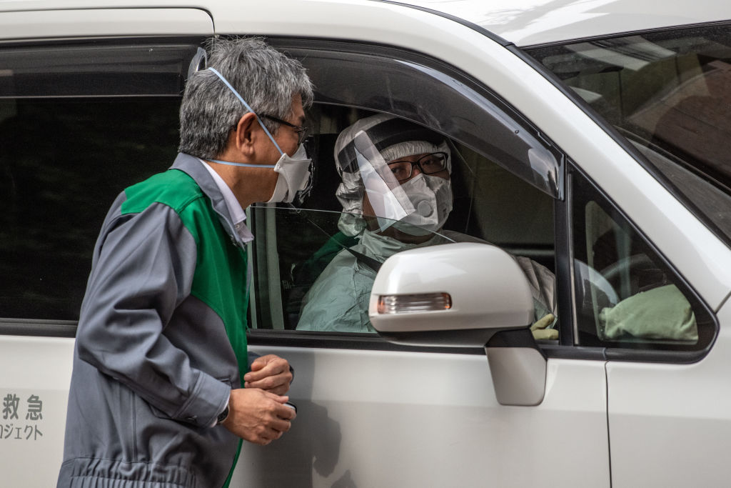 Un automovilista utiliza un traje completo de protección por el coronavirus en la ciudad de Tokio