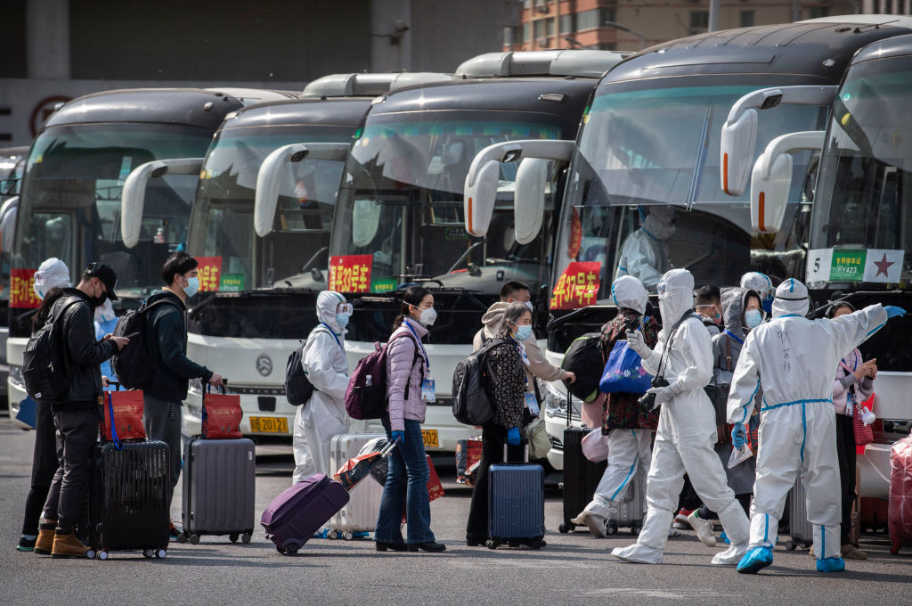Trabajadores de la salud supervisan un terminal de buses en la ciudad de Wuhan