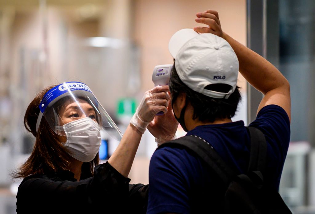 Trabajadora toma la temperatura de un cliente en Tokio