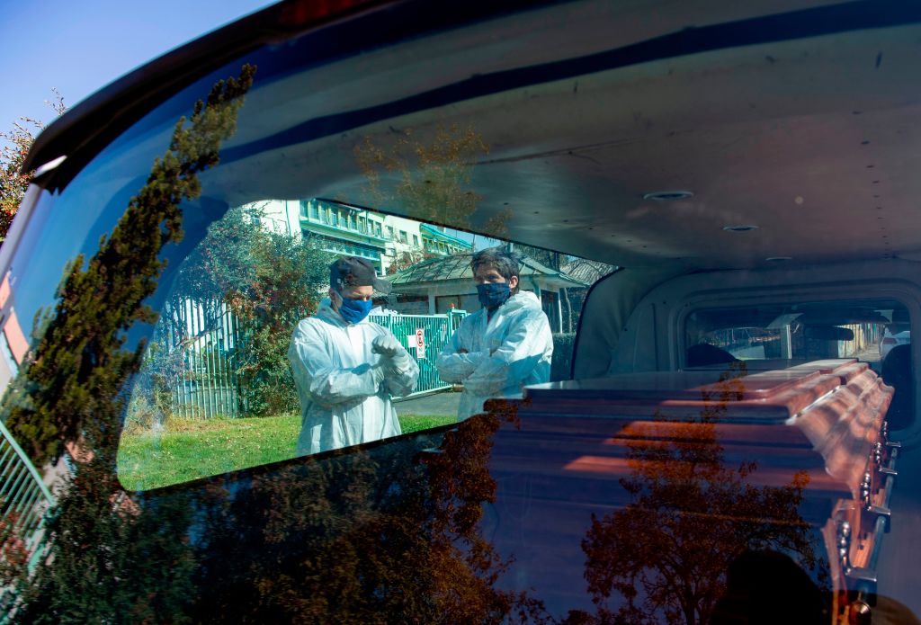 Trabajadores de una morgue observan una carroza fúnebre en Santiago
