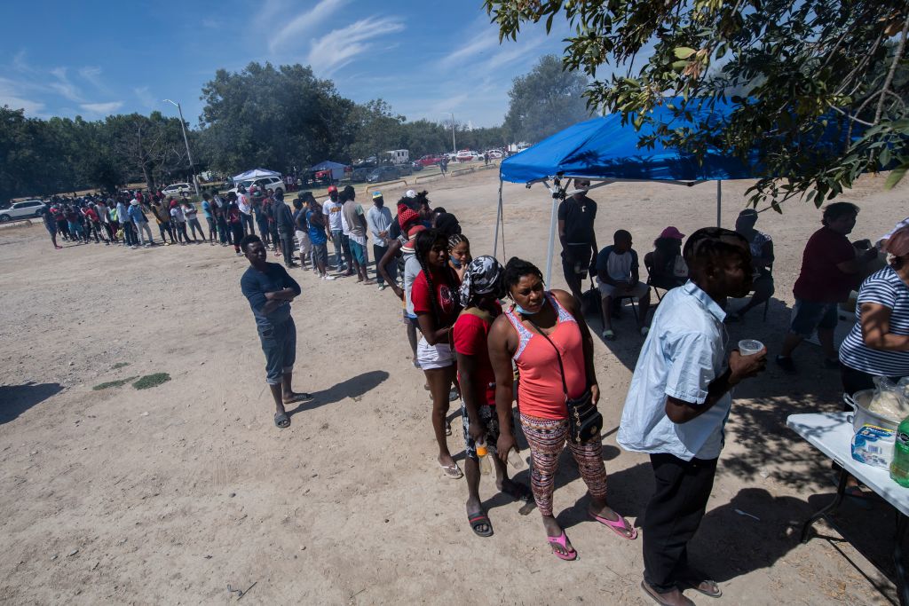 Migrantes esperan en una fila para recibir comida en Ciudad Acuña