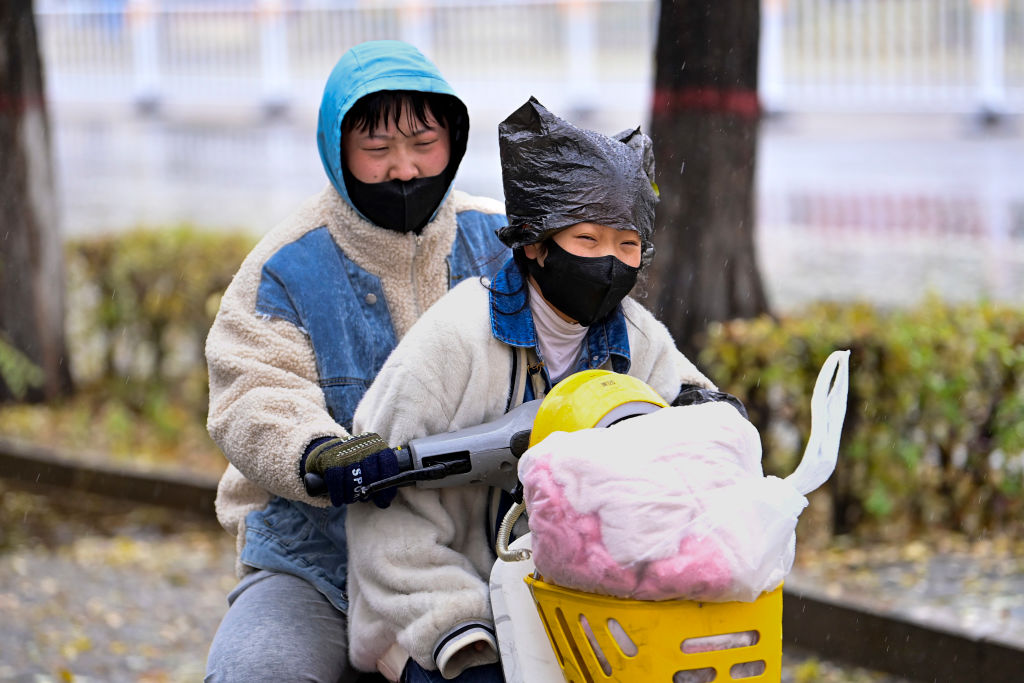 Familia viaja en bicicleta con mascarillas en la ciudad Hohhot de China
