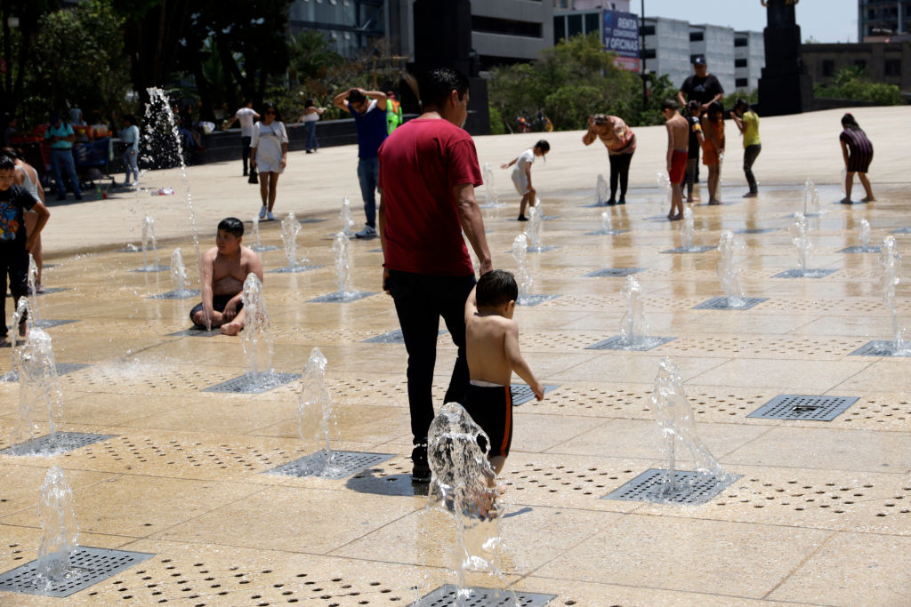 Niños juegan en el agua en las calles ante el fuerte calor en Ciudad de México